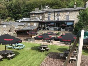 ein Gebäude mit Tischen und Sonnenschirmen davor in der Unterkunft Grapes Hotel, Bar & Restaurant Snowdonia Nr Zip World in Blaenau-Ffestiniog