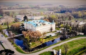 an aerial view of a large building with a river at Hotel Zamek Królewski w Rydzynie in Rydzyna