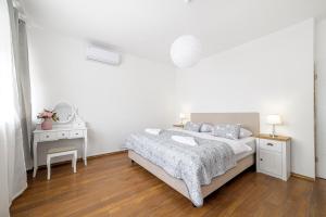a white bedroom with a bed and a desk at Hostel Globo in Šibenik