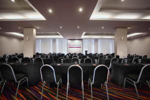 una sala de conferencias con mesas y sillas negras y una pantalla en favehotel - Pantai Losari Makassar, en Makassar