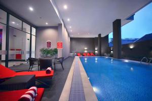 een groot zwembad in een hotel met rode meubels bij favehotel - Pantai Losari Makassar in Makassar