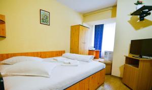 a bedroom with a large white bed and a television at Hotel Decebal Bistrita in Bistriţa