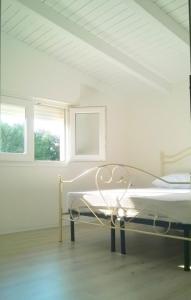ein weißes Zimmer mit einem Bett und zwei Fenstern in der Unterkunft Dimora Arnesano in Torre Lapillo