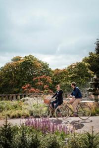 two men riding bikes on a path near a fountain at The Gleneagles Hotel in Auchterarder