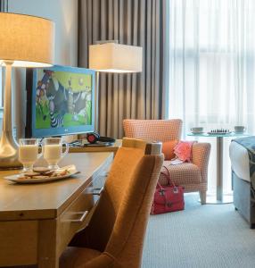 a hotel room with a desk with a tv and chairs at Clayton Hotel Limerick in Limerick