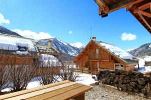 une cabane en rondins dans la neige avec un banc dans l'établissement Le Barlèt23 pers Hameau des Chazals Nevache Hautes Alpes, à Névache
