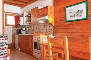 - une cuisine avec des placards en bois, une table et des chaises dans l'établissement Le Gouroùn Hameau des Chazals Nevache Hautes Alpes, à Névache
