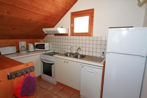 La cuisine est équipée d'un réfrigérateur blanc et d'un évier. dans l'établissement Le Sorè Hameau des Chazals Nevache Hautes Alpes, à Névache