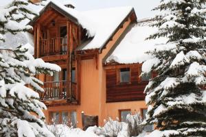 une cabane en rondins dans la neige avec des arbres dans l'établissement Le Queyrellin hameau des Chazals Nevache Hautes Alpes, à Névache