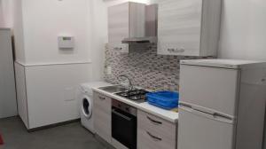 una cucina bianca con piano cottura forno superiore accanto a una lavatrice di Caterinette a Bisceglie