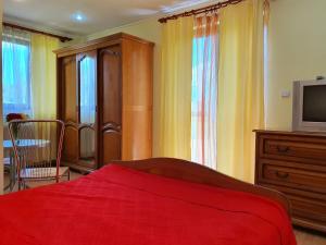 a bedroom with a red bed and a tv at Casa Carpati in Zărneşti