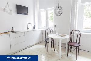 a white kitchen with a table and two chairs at Apartamenty Zacisze in Łódź