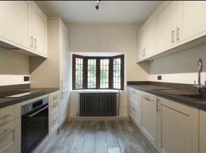 a large kitchen with white cabinets and a window at Luxury 3 Bed House on the Estate of 17th Century Manor House in Colchester