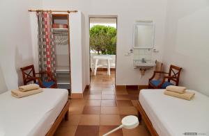 two beds in a room with a sink and a mirror at Can Nigg in Playa Migjorn