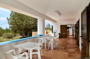 a balcony with white tables and white chairs at Can Nigg in Playa Migjorn
