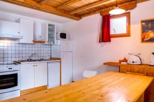 a kitchen with white appliances and a wooden table at Le Pignotto Hameau des Chazals Nevache Hautes Alpes in Névache