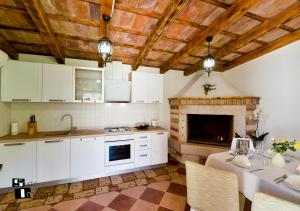 a kitchen with white cabinets and a fireplace at Charming stone cottage by the sea in Umag