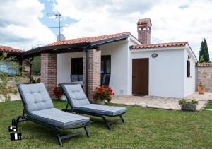 a pair of chairs in the yard of a house at Charming stone cottage by the sea in Umag