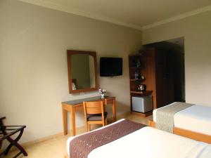 a bedroom with two beds and a desk and a mirror at U Village Hotel and Villa in Bandung