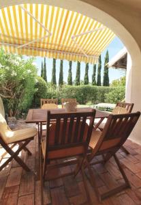 a wooden table and chairs under a yellow umbrella at Typical Portuguese Beach House just 88m to the beach in Porches