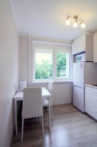 eine kleine Küche mit einem Tisch und einem weißen Kühlschrank in der Unterkunft Apartamentai Domeva in Druskininkai