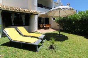 a patio with two chairs and an umbrella at Typical Portuguese Beach House just 88m to the beach in Porches