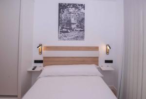a bedroom with a white bed and a picture on the wall at APARTAMENTOS LLAMIEVA in Posada de Llanes