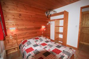 Le Taquo Hameau des Chazals Nevache Hautes Alpes في نافاشي: غرفة نوم بسرير وجدار خشبي