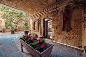 a stone building with a planter with flowers in it at L' Hôtellerie Easy Suites in Palermo