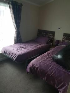 a bedroom with two beds with purple sheets and a window at Sea views, fabulous modern lodge in Port Seton