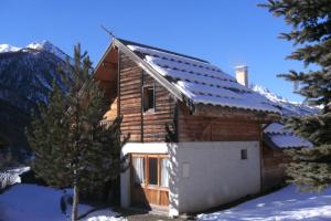 a log cabin in the snow with a mountain at Le Baoùba Hameau des Chazals Nevache Hautes Alpes in Névache