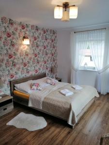 a bedroom with a bed with floral wallpaper and a window at Olimpijska pokoje in Szczyrk