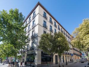 un edificio blanco en una calle con árboles en Uma Suites Atocha, en Madrid