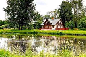 a house is sitting next to a pond at Klimatyczna Willa w stylu BOHO in Wysokie Mazowieckie