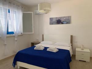ファヴィニャーナにあるFavignana Holidaysのベッドルーム1室(ブルーベッド1台、タオル付)