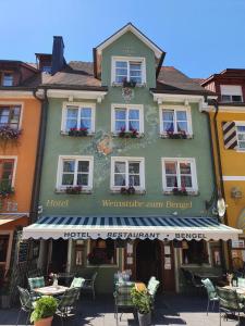 a green building with tables and chairs in front of it at Hotel Zum Bengel in Meersburg