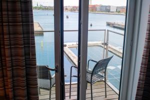 a balcony with two chairs and a view of the water at Copenhagen Island Hotel in Copenhagen