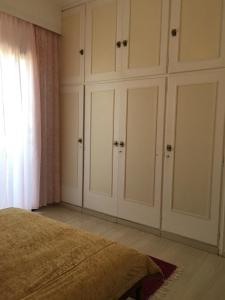 Schlafzimmer mit weißen Schränken und einem Bett in der Unterkunft Chris Studios & Apartments in Lechaio