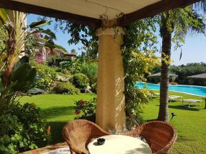 a table and chairs under an umbrella in a yard at Hotel Mariposas in Villasimius