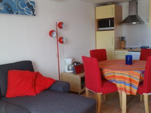 a living room with a table and red chairs at Résidence La Grande Voile in Banyuls-sur-Mer