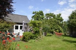 um quintal com uma rede e uma casa em Vakantiehuis Merel em Den Helder