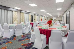 a banquet hall with white chairs and tables and red flowers at La Quinta by Wyndham Seattle Federal Way in Federal Way
