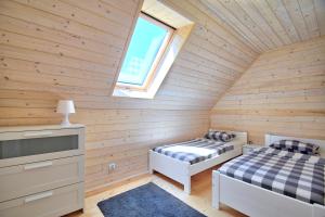 two beds in a wooden room with a window at Domki Apartamenty Akacja in Sianozety