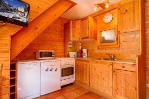 a kitchen with wooden cabinets and a white appliances at L'Elva Hameau des Chazals Nevache Hautes Alpes in Névache +18 photos