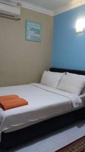 - une chambre avec un lit doté de draps blancs et d'une couverture orange dans l'établissement Manja Inn, Paka, à Paka