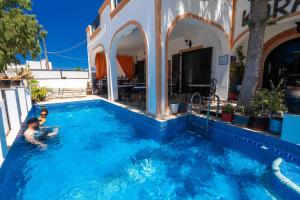 a swimming pool with two people in the water at Tritonas Rooms in Kamari