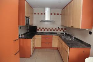 uma pequena cozinha com armários laranja e um lavatório em San Pedroko Bidea em Alsasua