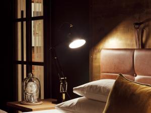 a bedroom with a bed and a lamp next to a window at Gastwerk Hotel Hamburg in Hamburg