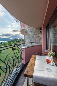 einen Balkon mit einem Tisch und 2 Gläsern Wein in der Unterkunft MOBI DICK Family Hotel in Glavatartsi