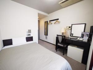 1 dormitorio con 1 cama y escritorio con ordenador en Hotel Route-Inn Shimada Ekimae, en Shimada